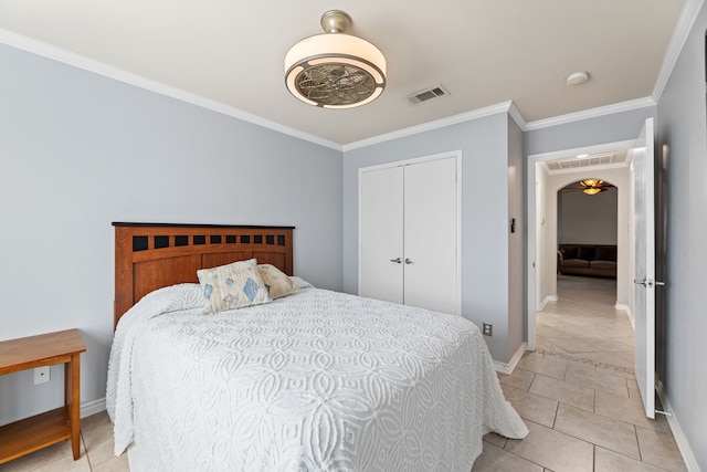 bedroom featuring a closet, light tile patterned floors, and ornamental molding