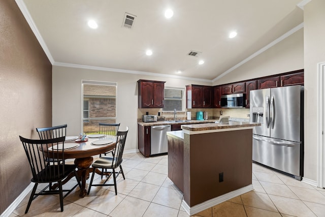 kitchen featuring a kitchen island, vaulted ceiling, light tile patterned floors, appliances with stainless steel finishes, and crown molding