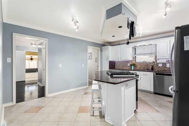 kitchen with stainless steel appliances, a breakfast bar, a kitchen island, light tile patterned floors, and white cabinets