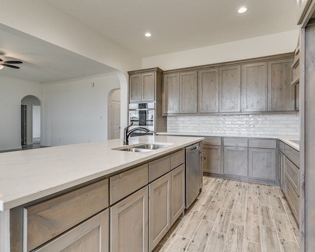 kitchen featuring light wood-type flooring, stainless steel appliances, light stone countertops, sink, and tasteful backsplash