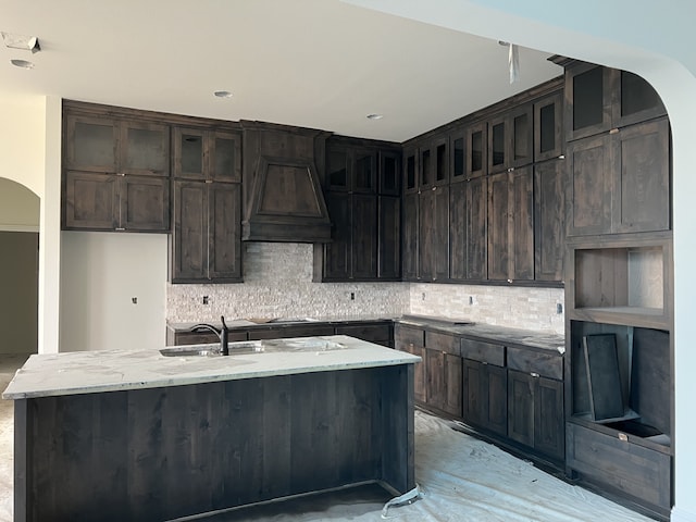 kitchen featuring sink, a center island with sink, backsplash, and custom exhaust hood