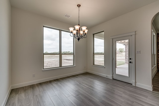 unfurnished dining area featuring a notable chandelier, a water view, and light hardwood / wood-style floors