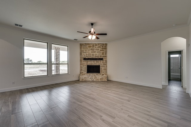 unfurnished living room featuring a fireplace, ornamental molding, light hardwood / wood-style floors, and ceiling fan