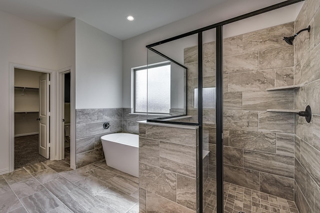 bathroom featuring separate shower and tub and tile walls