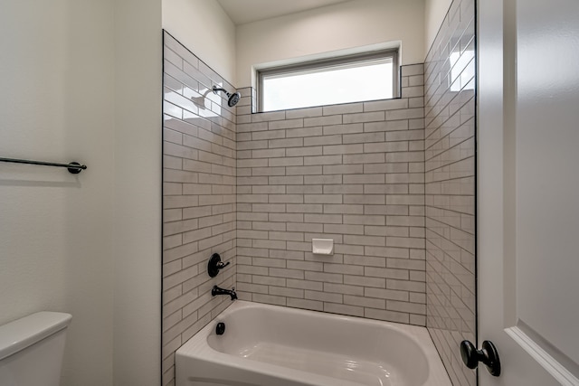 bathroom featuring tiled shower / bath combo and toilet