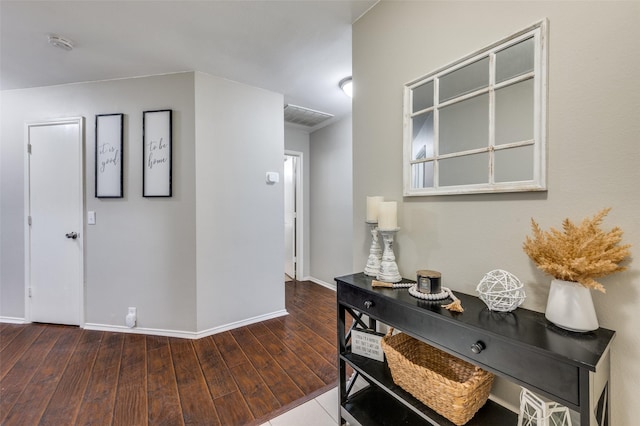 corridor featuring dark wood-type flooring, visible vents, and baseboards