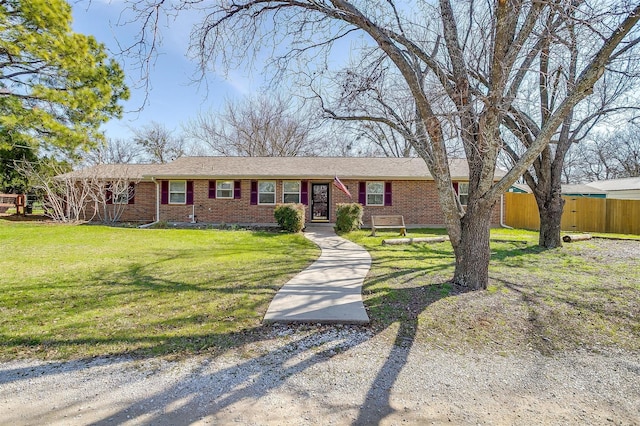 ranch-style home featuring a front yard, fence, and brick siding