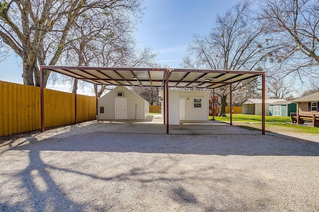 view of vehicle parking featuring gravel driveway, fence, and a storage shed