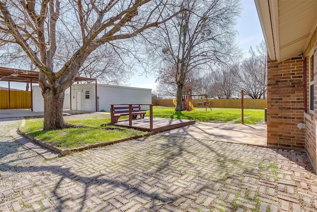 view of patio with an outbuilding, a playground, and fence