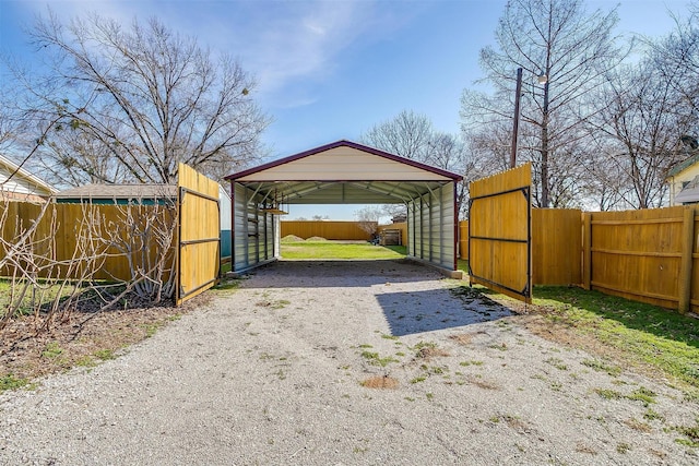 exterior space featuring driveway, fence, and a detached carport