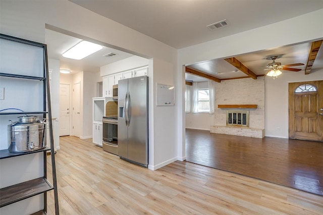 kitchen with visible vents, white cabinets, open floor plan, stainless steel appliances, and light wood-style floors