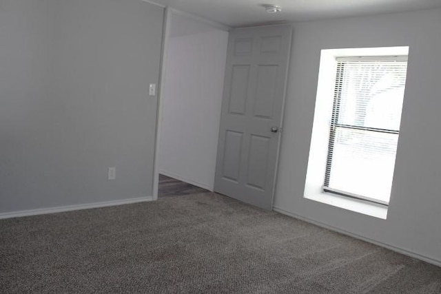 spare room featuring dark colored carpet