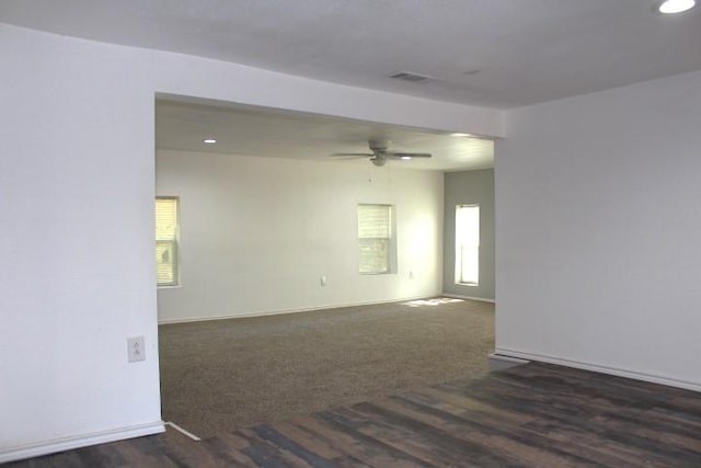 empty room featuring ceiling fan and dark colored carpet