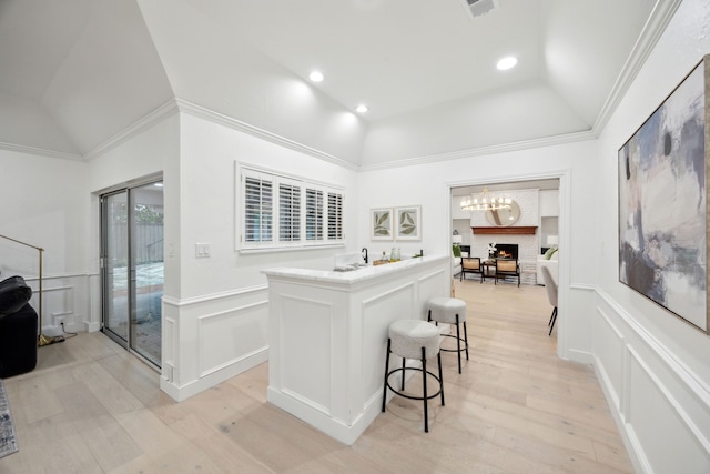 kitchen featuring lofted ceiling, a breakfast bar, light hardwood / wood-style flooring, a kitchen island, and white cabinets