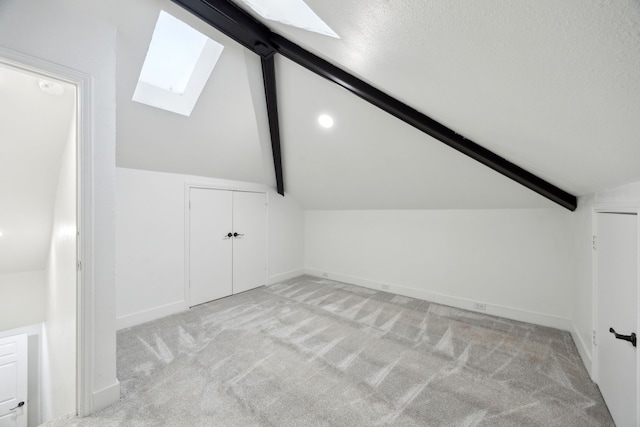 bonus room featuring vaulted ceiling with skylight and light carpet