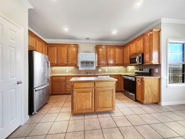 kitchen featuring appliances with stainless steel finishes, sink, light tile patterned flooring, a center island, and crown molding