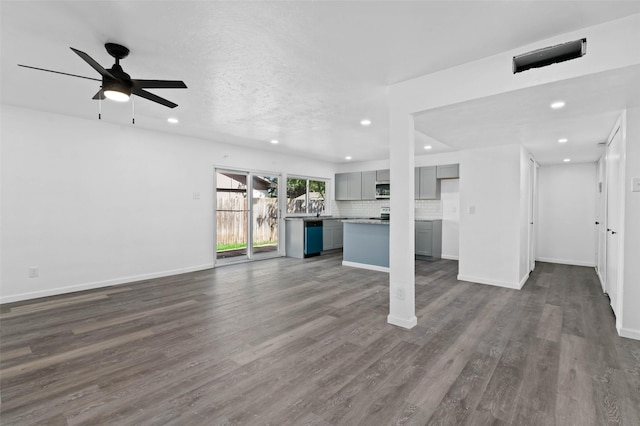 unfurnished living room with ceiling fan, dark wood-type flooring, and a textured ceiling