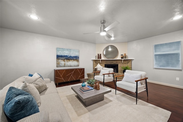 living room with recessed lighting, wood finished floors, a ceiling fan, baseboards, and a brick fireplace