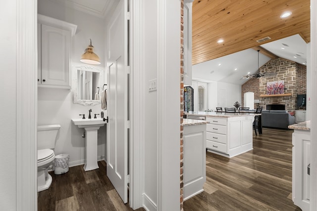 bathroom with visible vents, toilet, wood finished floors, vaulted ceiling, and a fireplace
