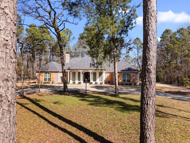 view of front of home featuring brick siding, a chimney, and a front yard