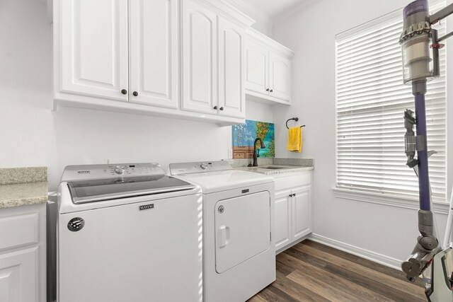 clothes washing area with dark wood-style floors, washer and clothes dryer, cabinet space, a sink, and baseboards
