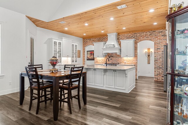 dining space with dark wood-type flooring, arched walkways, wooden ceiling, and recessed lighting