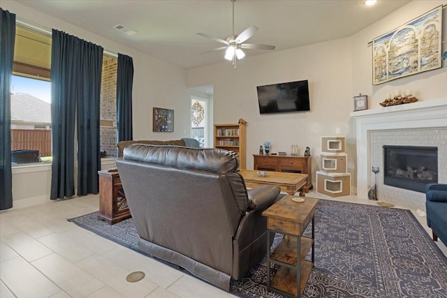 4024 Rosin St, Aubrey, TX 76227 - living room featuring a glass covered fireplace, a ceiling fan, visible vents, and light tile patterned floors