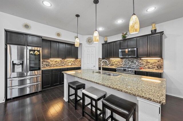 4424 Dashland Dr, Celina, TX 75009 - kitchen with appliances with stainless steel finishes, sink, decorative light fixtures, an island with sink, and light stone countertops