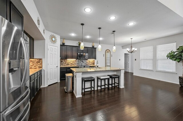 4424 Dashland Dr, Celina, TX 75009 - kitchen with an island with sink, stainless steel appliances, decorative light fixtures, light stone counters, and a kitchen breakfast bar