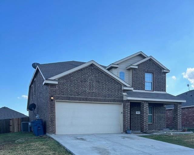 front of property featuring central air condition unit, a front yard, and a garage