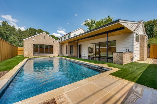 view of swimming pool with a patio, a lawn, and exterior bar