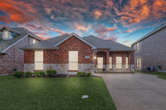 view of front of property featuring a lawn and central AC