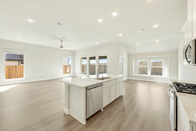 kitchen with visible vents, a sink, open floor plan, ceiling fan, and appliances with stainless steel finishes