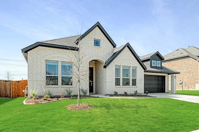 french country home with driveway, fence, a front lawn, and brick siding
