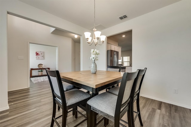 dining area with light wood-type flooring and a notable chandelier