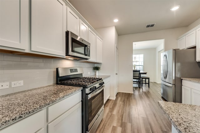 kitchen with stainless steel appliances, light hardwood / wood-style flooring, tasteful backsplash, light stone counters, and white cabinets