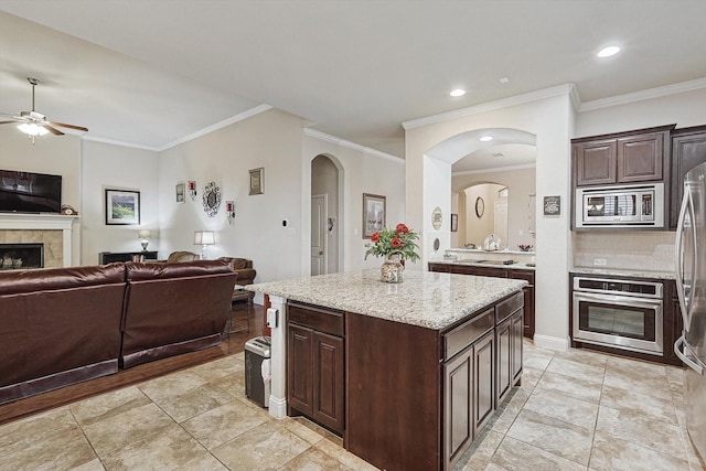 kitchen with stainless steel appliances, a center island, open floor plan, and dark brown cabinets