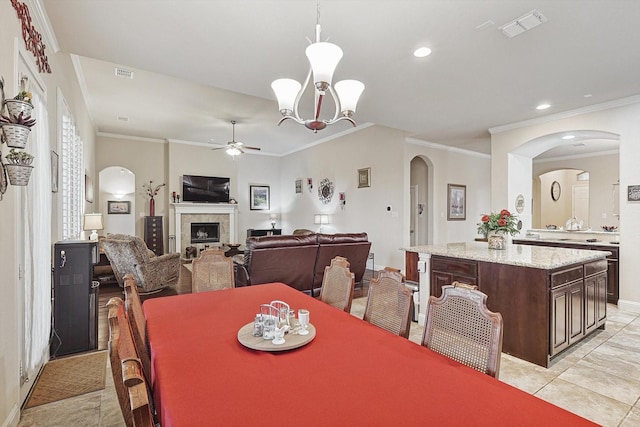 dining room with light tile patterned floors, a fireplace, visible vents, and ceiling fan with notable chandelier