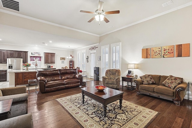 living area with ornamental molding, dark wood-style flooring, visible vents, and ceiling fan with notable chandelier