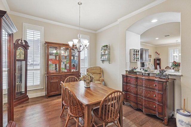 dining area featuring a chandelier, arched walkways, dark wood finished floors, and ornamental molding