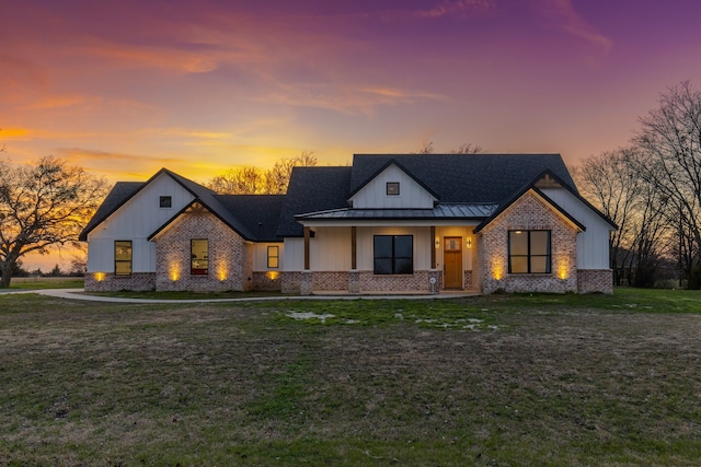 modern inspired farmhouse with a lawn and covered porch