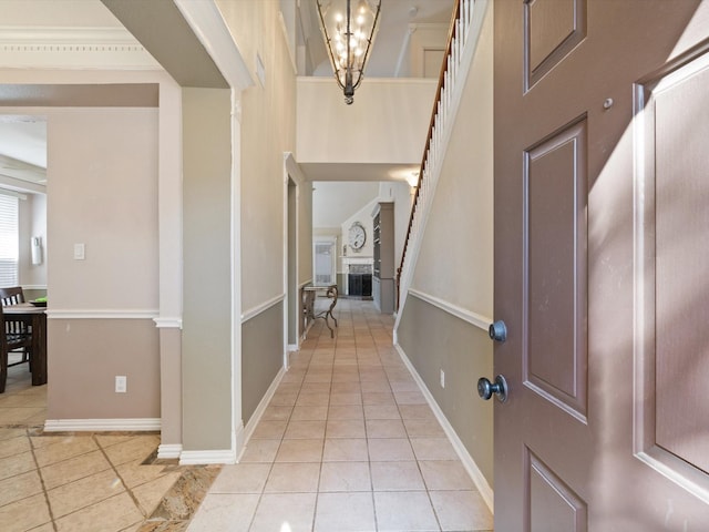 foyer with an inviting chandelier, a fireplace, baseboards, and light tile patterned flooring