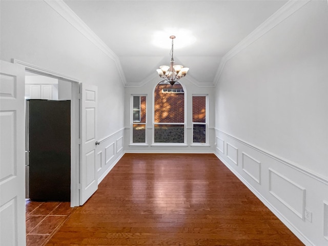 unfurnished dining area featuring a chandelier, vaulted ceiling, a decorative wall, and ornamental molding