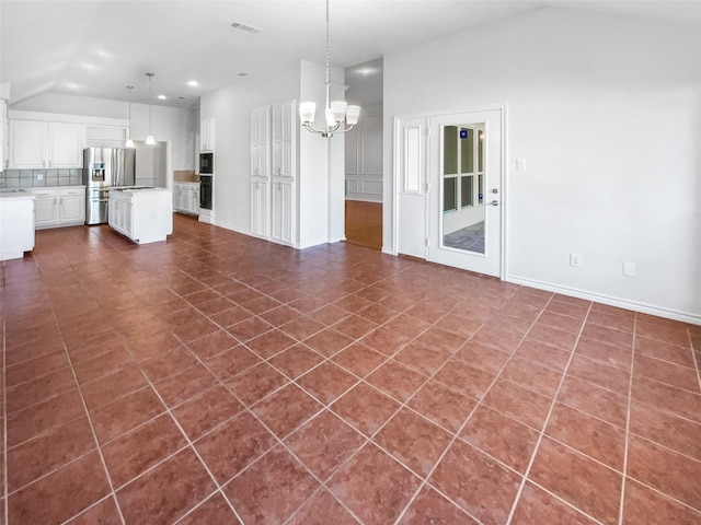 unfurnished living room featuring lofted ceiling, baseboards, a chandelier, and dark tile patterned flooring