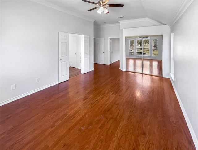 interior space featuring dark wood finished floors, vaulted ceiling, crown molding, and baseboards