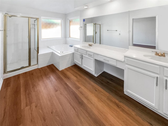 full bath featuring double vanity, wood finished floors, a sink, and a bath