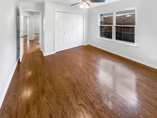 unfurnished bedroom featuring ceiling fan, a closet, baseboards, and dark wood-type flooring