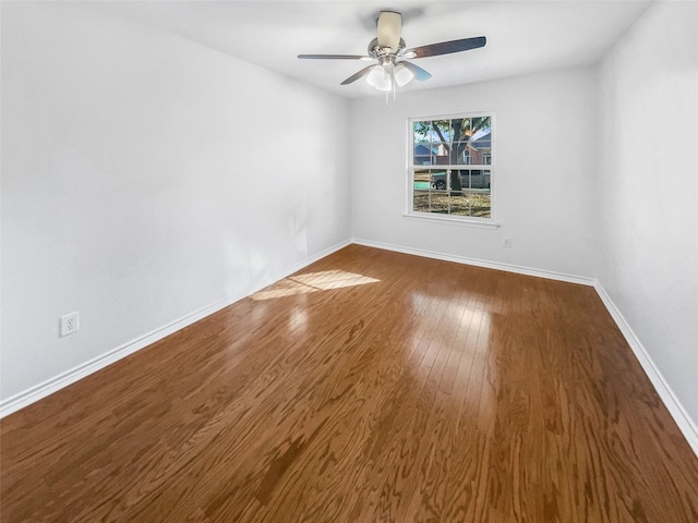 unfurnished room featuring ceiling fan, dark wood finished floors, and baseboards