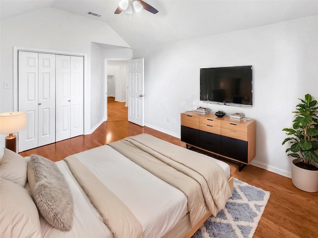 bedroom featuring lofted ceiling, wood finished floors, visible vents, a ceiling fan, and a closet