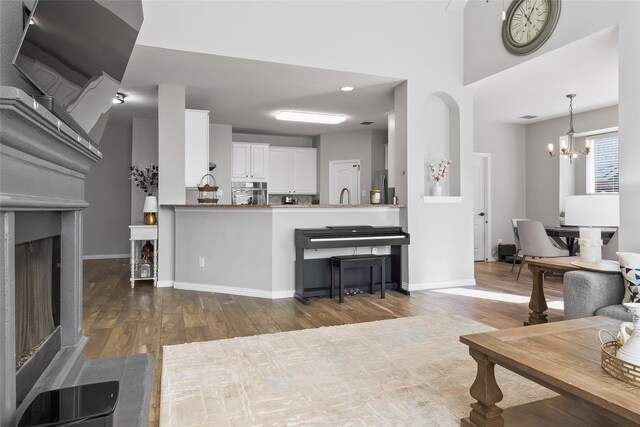 living area with dark wood-style floors, a fireplace, a chandelier, and baseboards